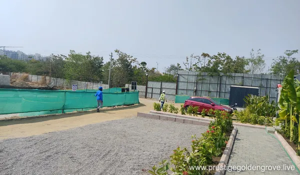 Wide-angle view of the Prestige Golden Grove construction site in Velimala, Hyderabad, showing initial ground leveling, boundary fencing, and heavy machinery prepared for the upcoming high-rise tower development.