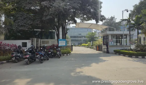 A modern commercial building IT HUB. The building is situated at a busy intersection with green trees and streetlights, serving as a landmark near the Prestige Golden Grove project area.