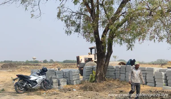 On-site construction progress at Prestige Golden Grove in Velimela-Kollur, Hyderabad, showing initial ground leveling and site barricading.